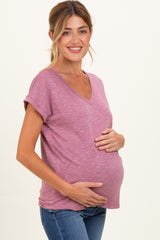 woman wearing a mauve v-neck maternity top and holding her baby bump