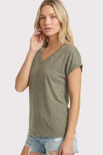 woman wearing an olive green v-neck t-shirt with rolled short sleeves paired with denim shorts