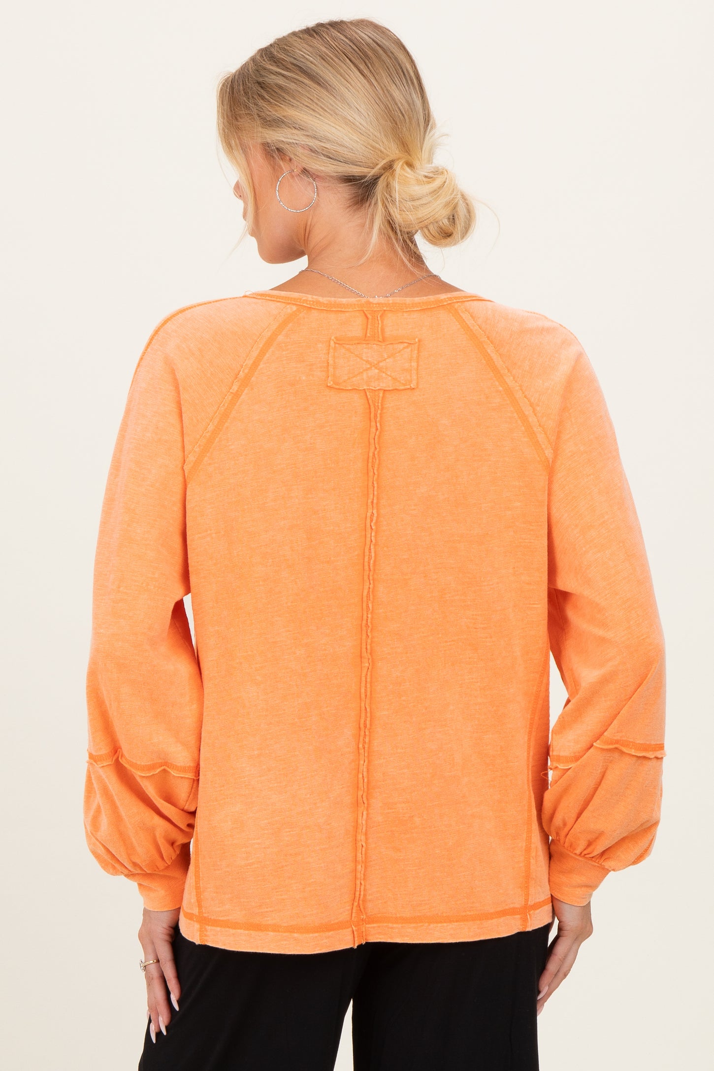 maternity wear in a vibrant orange long sleeve top with puffed sleeves and stitched detailing, view from the back