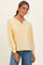 woman wearing a yellow long sleeve top with a v-neck and raglan sleeves, paired with light blue jeans