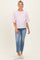 woman wearing a pink and white striped maternity top paired with light wash jeans and white sneakers