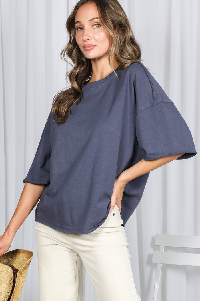 woman wearing a dark gray oversized short sleeve shirt with a relaxed fit and cream-colored pants