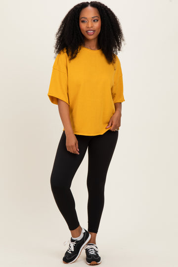 woman wearing an oversized mustard yellow t-shirt with black leggings and sneakers