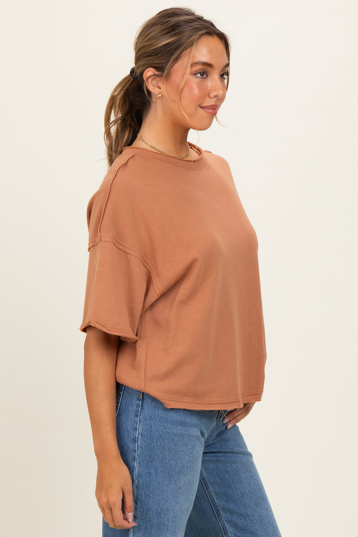 woman wearing a rust-colored oversized t-shirt and blue high-waisted jeans