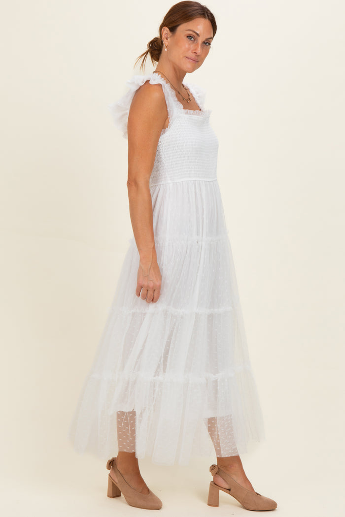 woman wearing a white tiered maxi dress with ruffled straps and polka dot details