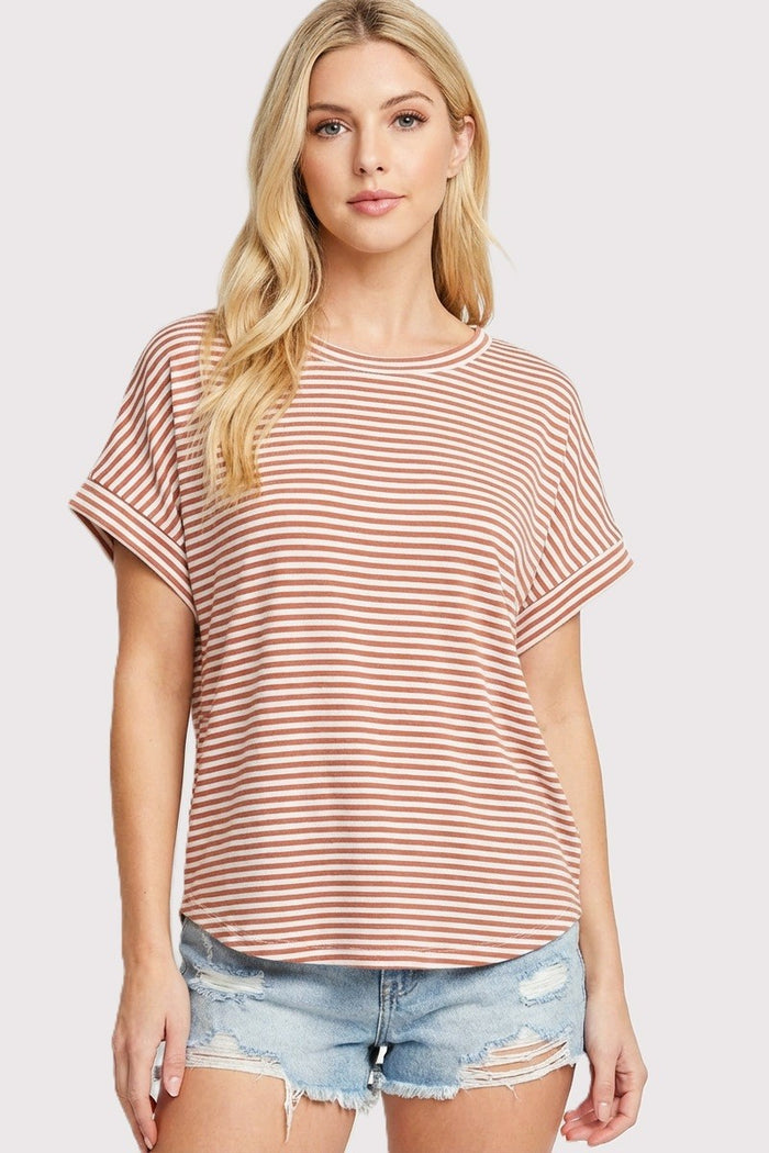 woman wearing a coral and white striped short sleeve top with rolled sleeves and distressed denim shorts