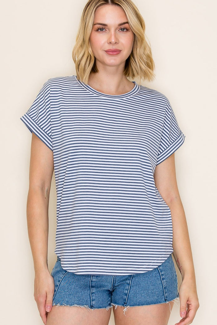 woman wearing a navy and white striped short sleeve top with rolled cuffs and styled with denim shorts