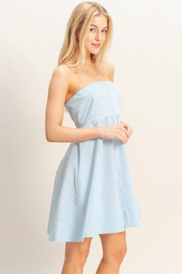 woman wearing a strapless light blue and white striped sundress with a fitted bodice and flared skirt