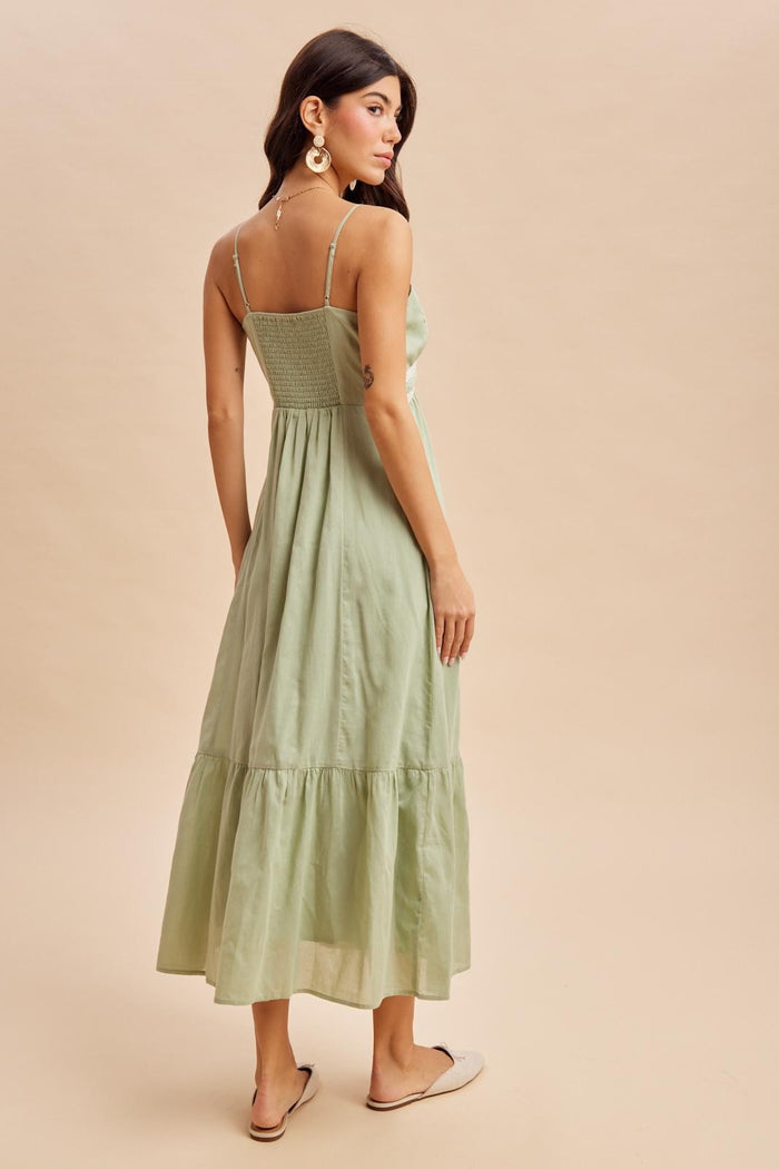 woman wearing a light green sleeveless maxi dress with a fitted bodice and tiered skirt, shown from the back