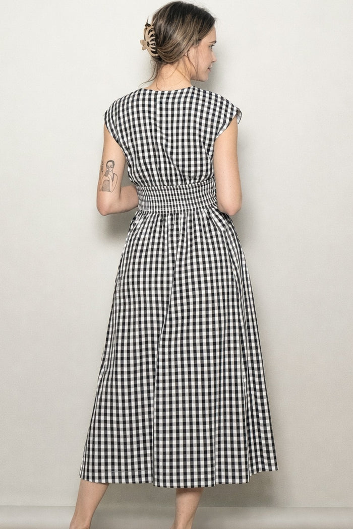 woman wearing a black and white gingham maxi dress with a smocked back and cap sleeves, viewed from the back