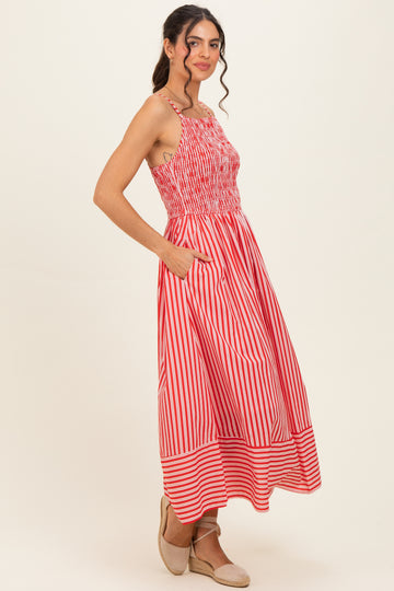 woman wearing a red and white striped smocked maxi dress with pockets and a flowy hemline