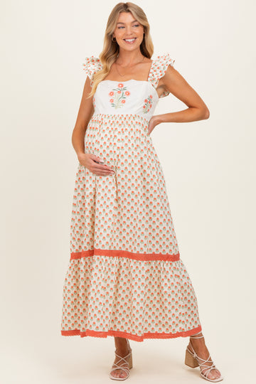 woman wearing a floral-motif maternity maxi dress with ruffled sleeves and a visible baby bump