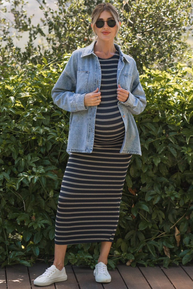 woman wearing a striped maternity maxi dress with a denim jacket and sneakers, showcasing her baby bump