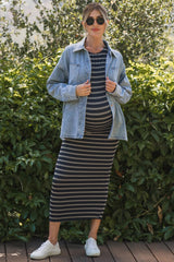 woman wearing a striped maternity maxi dress with a denim jacket and sneakers, showcasing her baby bump