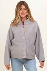 woman wearing a light gray maternity fleece jacket with a button-up front and contrasting trim