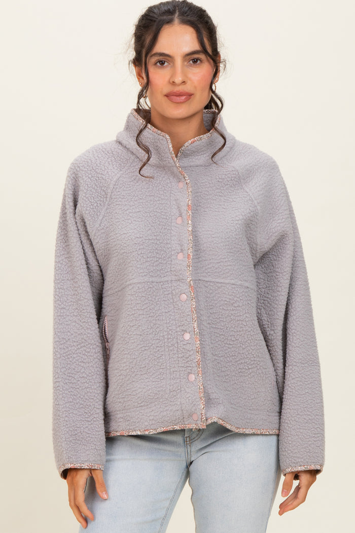 woman wearing a grey fleece jacket with button closure and pink trim details