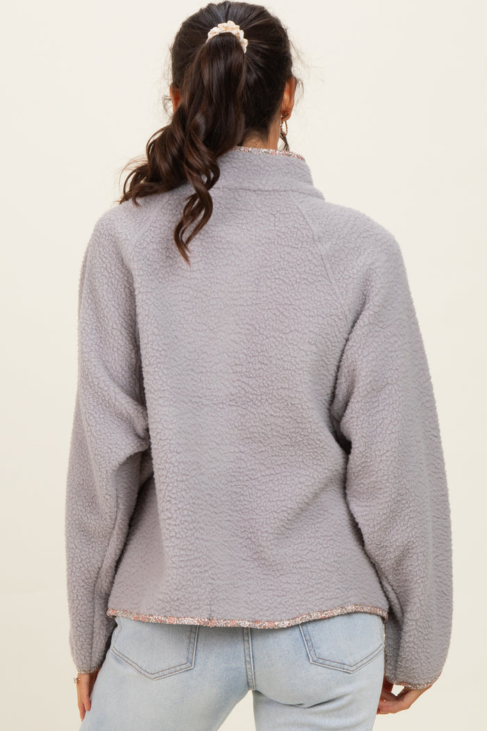woman wearing a gray fleece pullover with a collar and floral hem detail, shown from the back