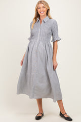 woman wearing a black and white gingham maternity dress with short sleeves and button-down front, showcasing a baby bump