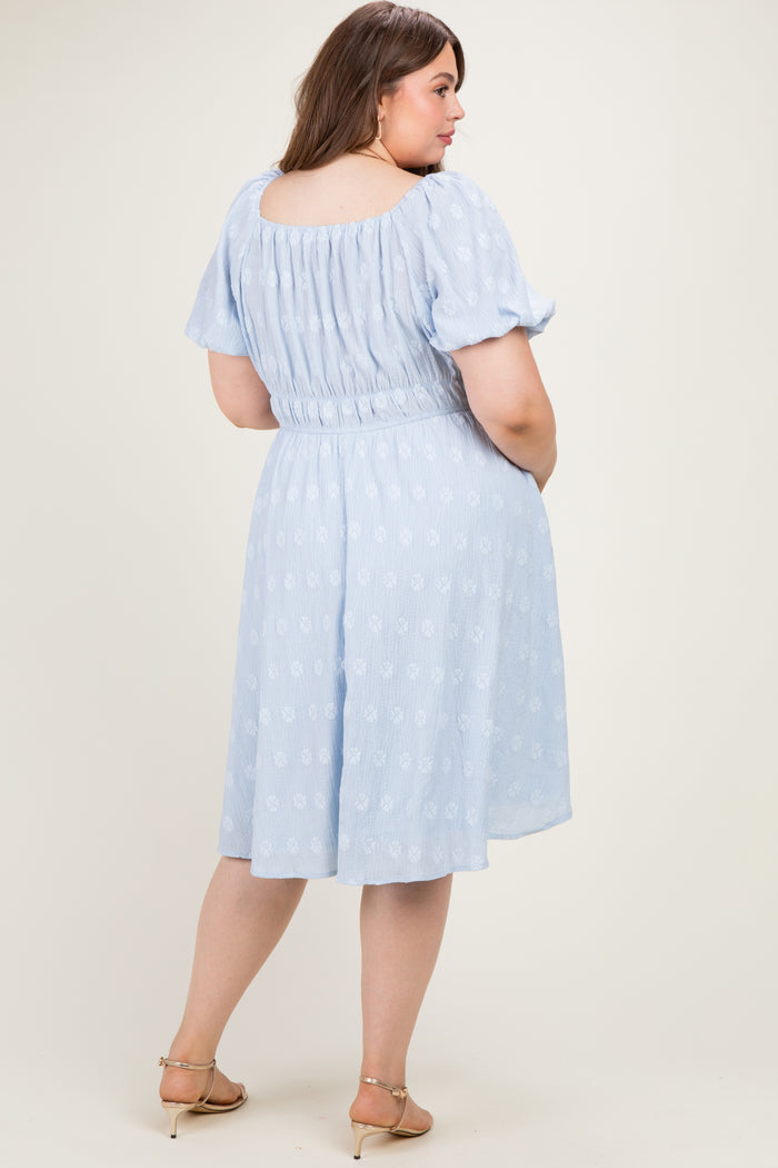 woman wearing a light blue floral print maternity dress with a fitted waist and puff sleeves, showing a baby bump