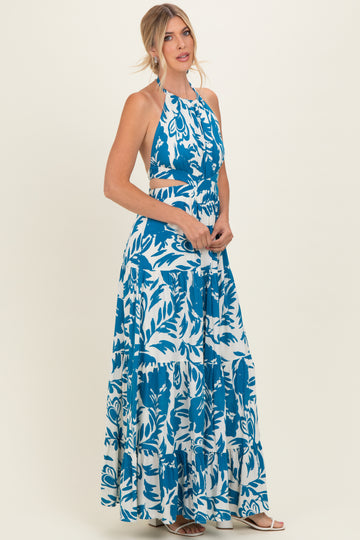 woman wearing a blue and white floral print maxi dress with a halter neck and cut-out details