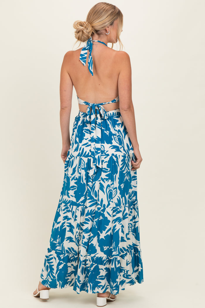 woman wearing a blue and white floral maxi dress with an open back and a halter neck tie