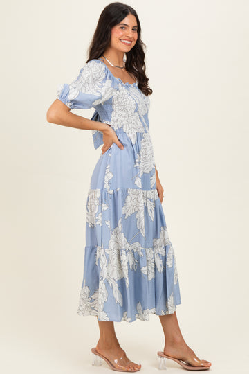 woman wearing a light blue floral print maxi dress with puff sleeves and a tiered skirt