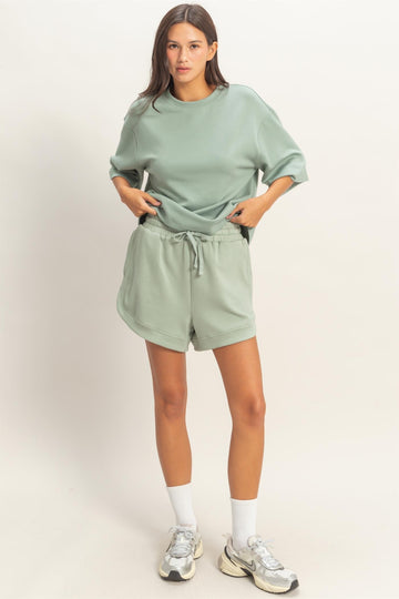 woman wearing a light green oversized t-shirt and matching shorts with an elastic waist and side pockets