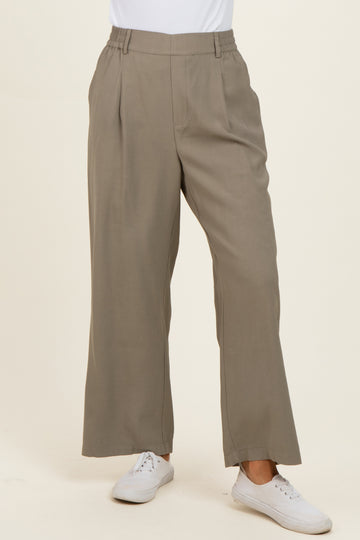 woman wearing light taupe wide-leg trousers with a pleated front and elastic waistband, paired with white sneakers