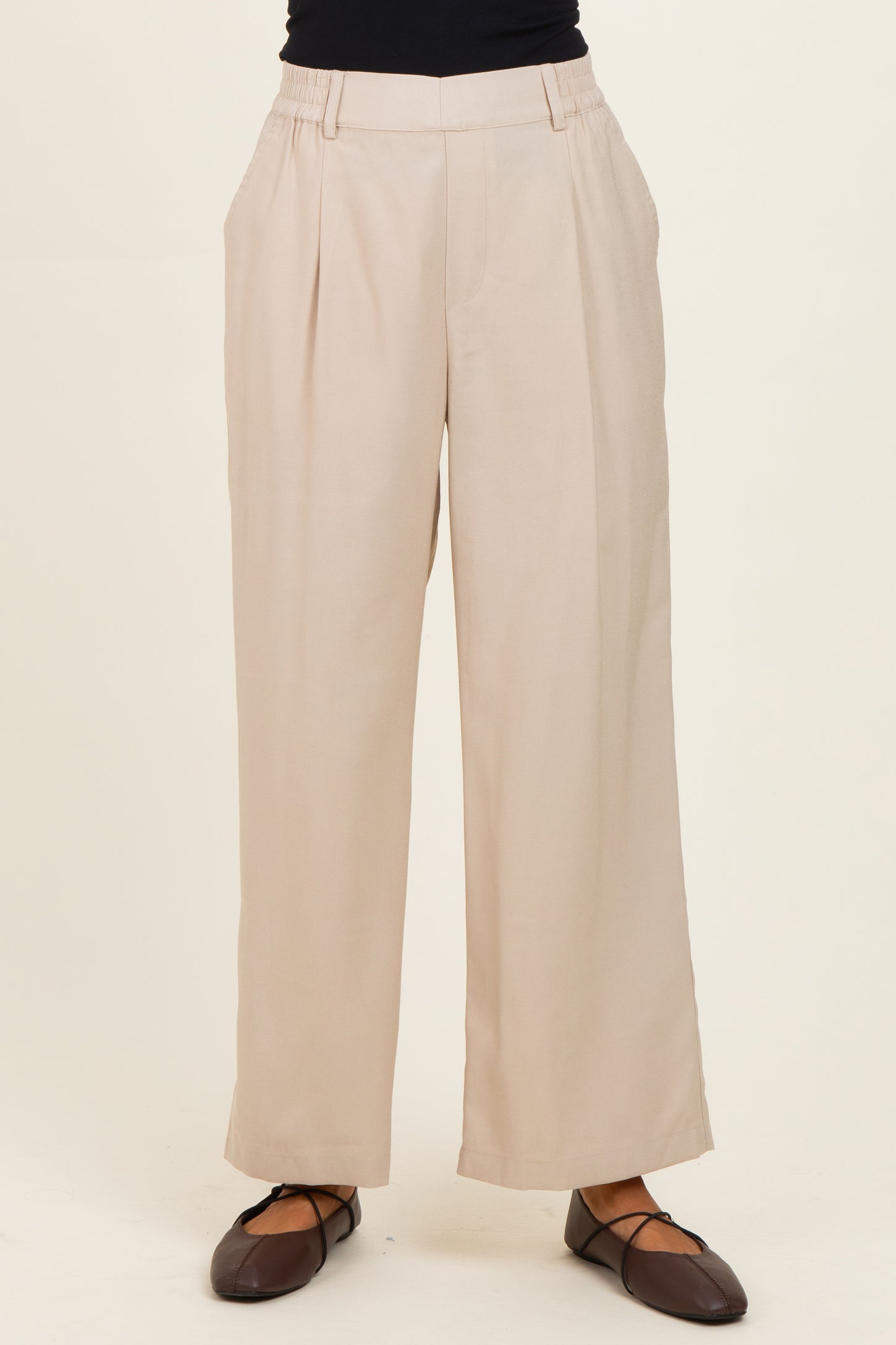 woman wearing beige wide-leg trousers with a high waist and side pockets