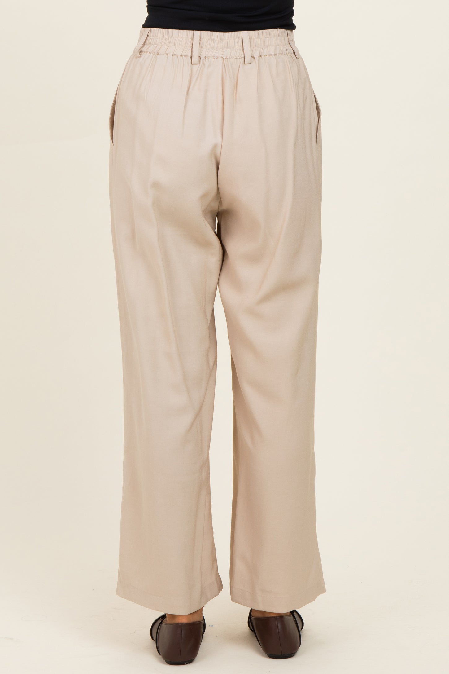 woman wearing beige wide-leg trousers, showing the back view and elastic waistband