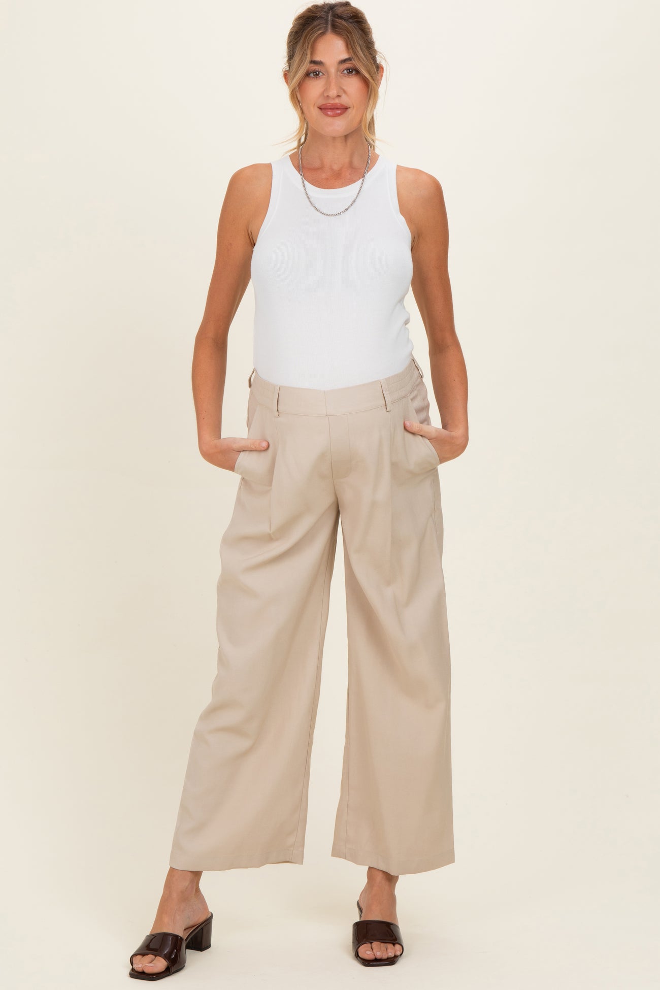 woman wearing a white ribbed tank top and beige wide-leg maternity pants with pockets