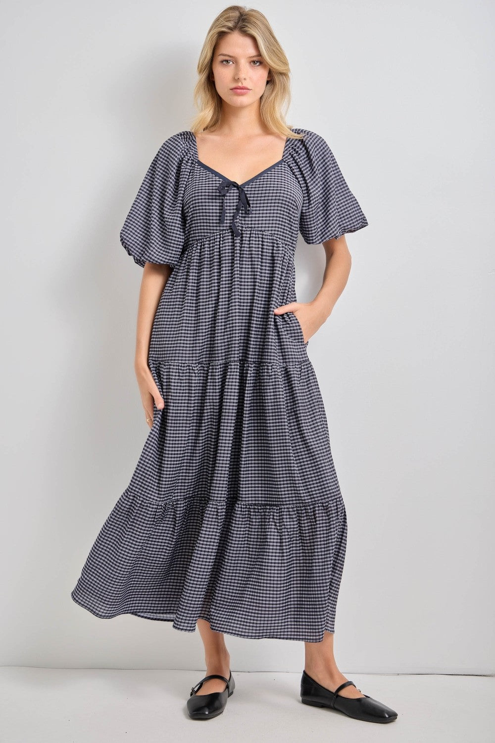 woman wearing a black and white checked maxi dress with puff sleeves and pockets