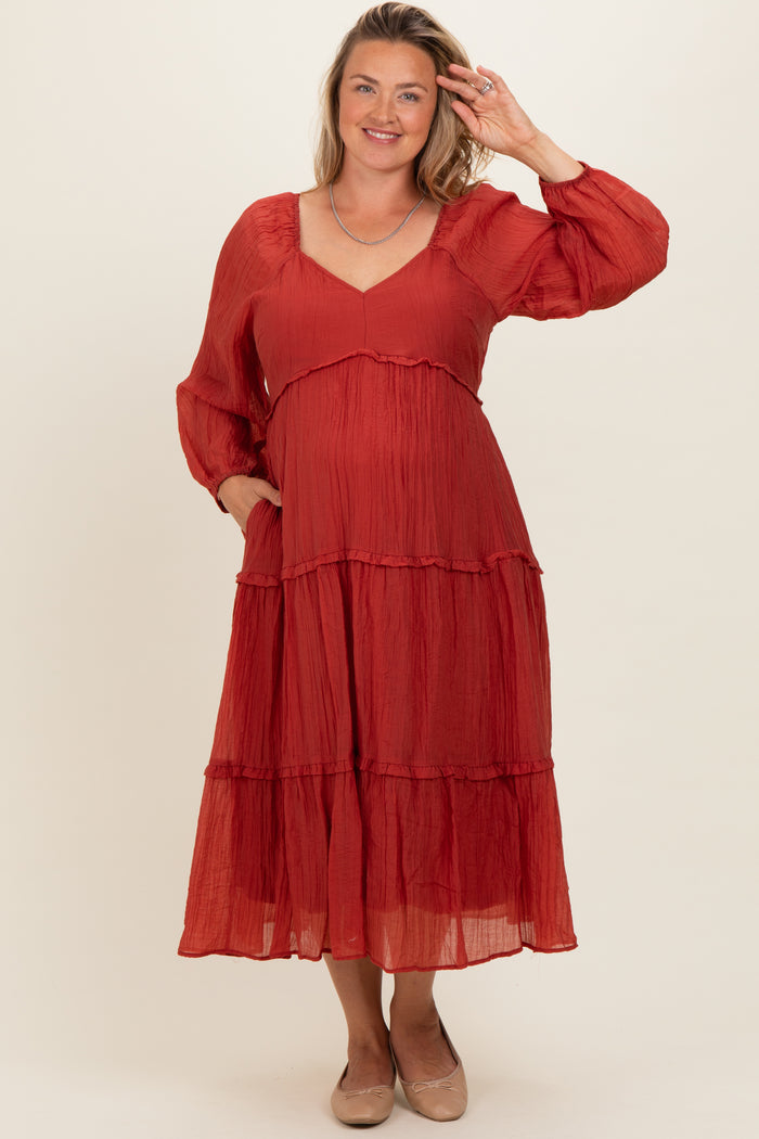 woman wearing a rust-colored tiered maternity dress with long sleeves and a baby bump visible