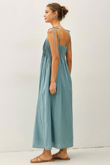 woman wearing a light blue maxi dress with tie shoulder straps and smocked bodice, shown from the back