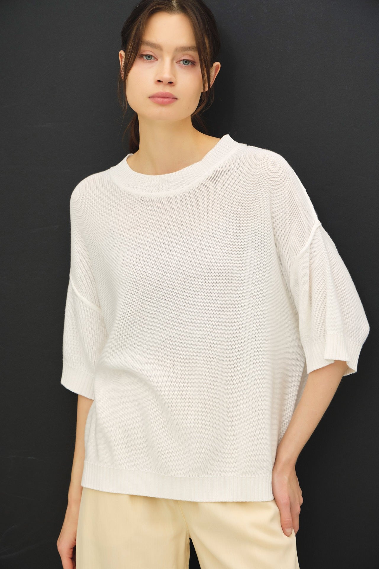 woman wearing a relaxed fit ivory oversized knit sweater with short sleeves and a wide neckline