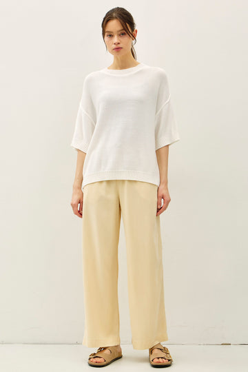 woman wearing a white oversized knit sweater paired with wide-leg beige trousers