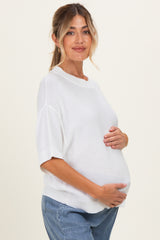 woman wearing a white short sleeve maternity sweater and holding her baby bump