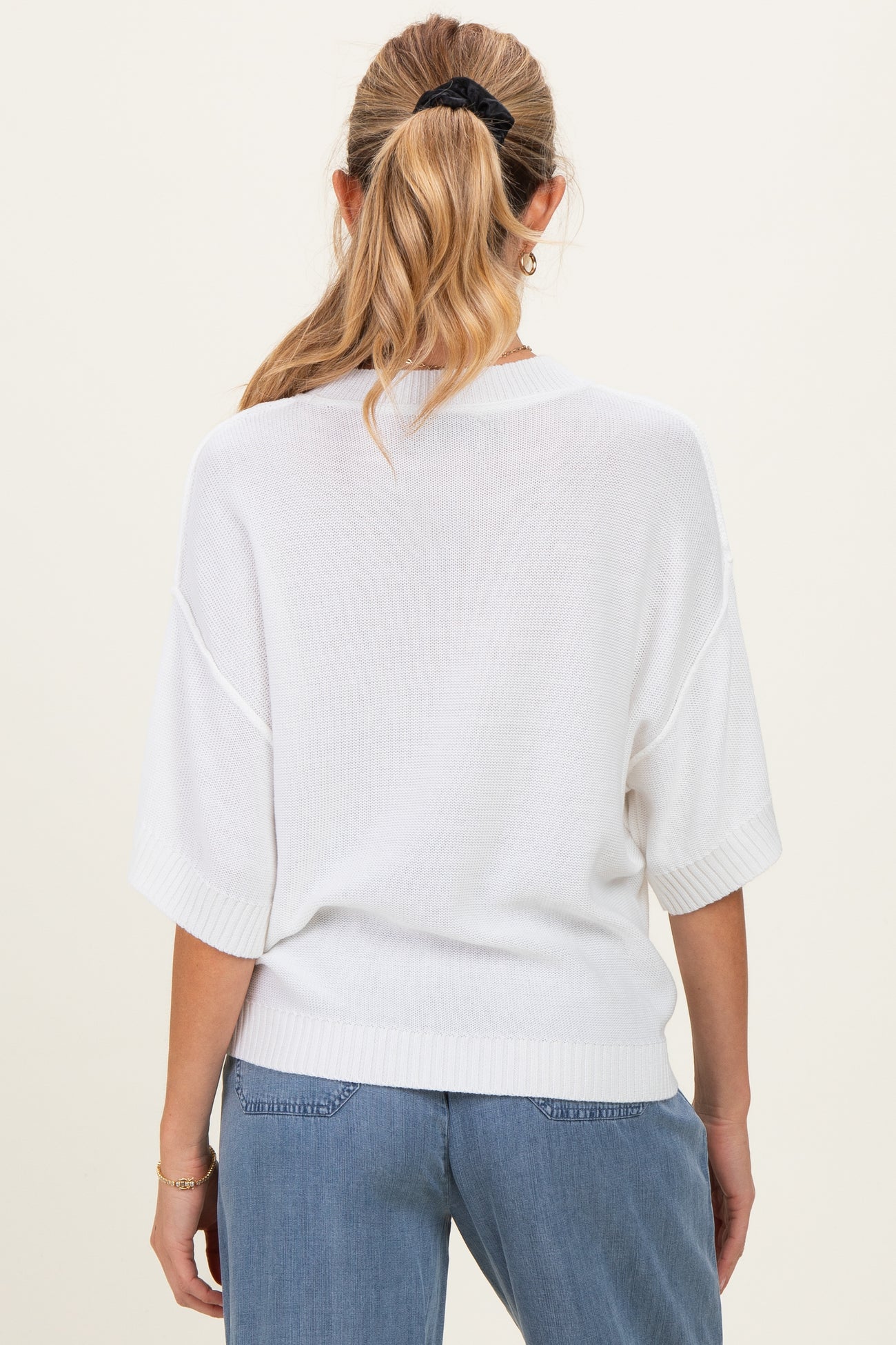 woman wearing a white oversized short sleeve maternity sweater, seen from the back with a relaxed fit