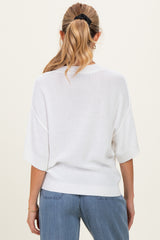woman wearing a white oversized short sleeve maternity sweater, seen from the back with a relaxed fit