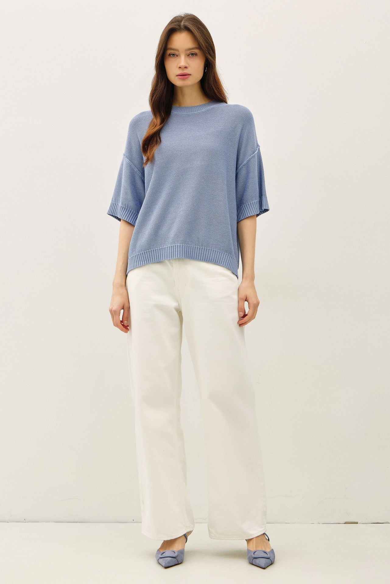 woman wearing a light blue oversized knit sweater and cream wide-leg pants, paired with blue flat shoes