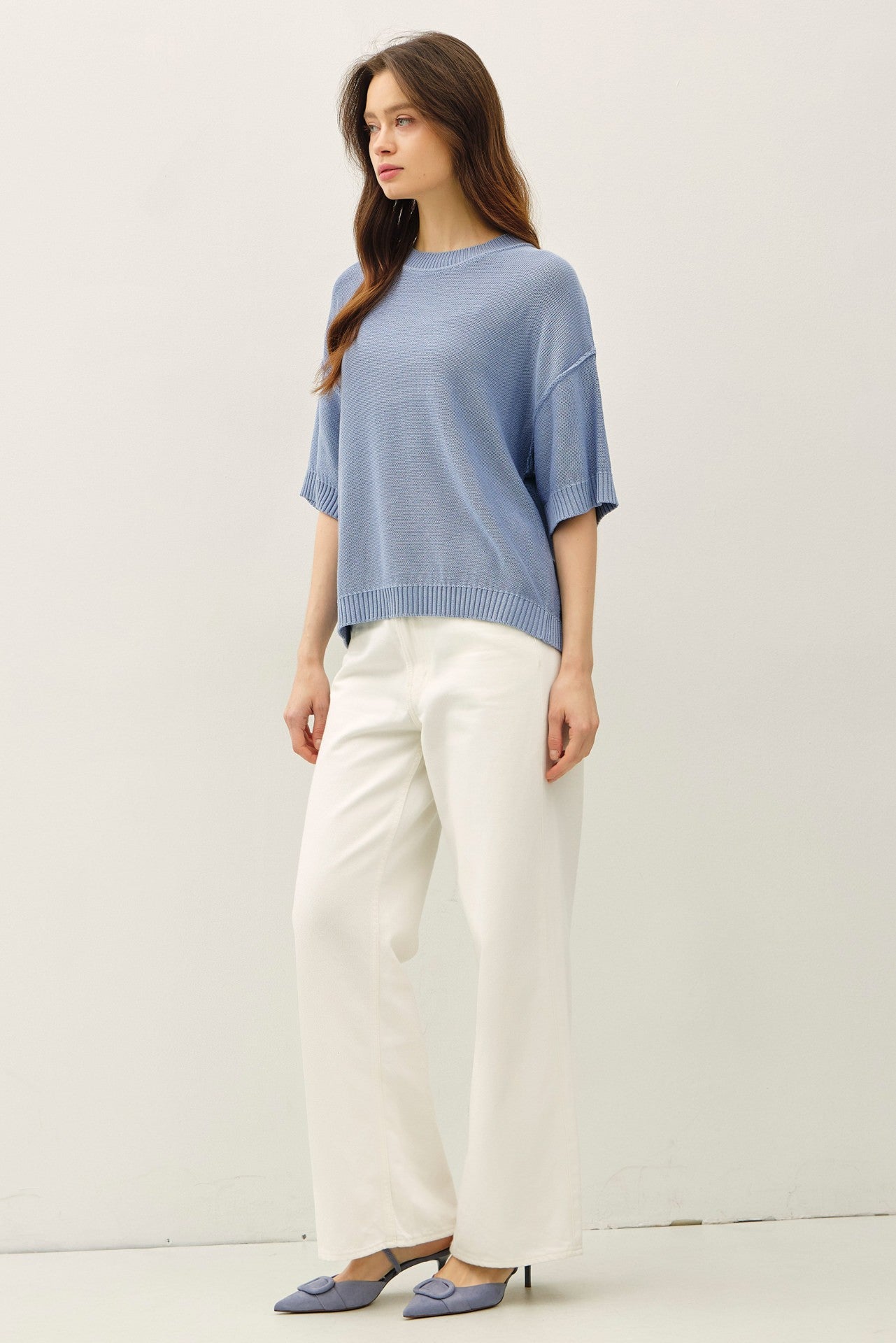 woman wearing a light blue oversized sweater with short sleeves and white wide-leg trousers