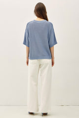 woman wearing a light blue oversized knit sweater with wide sleeves and cream-colored wide-leg pants