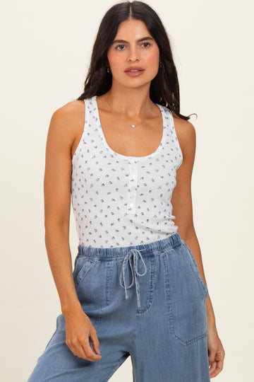 woman wearing a white tank top with blue floral print and buttons, paired with light blue drawstring pants