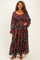 woman wearing a long sleeve plus size maxi dress with a paisley print in burgundy and green, featuring a cinched waist and ruffled sleeves