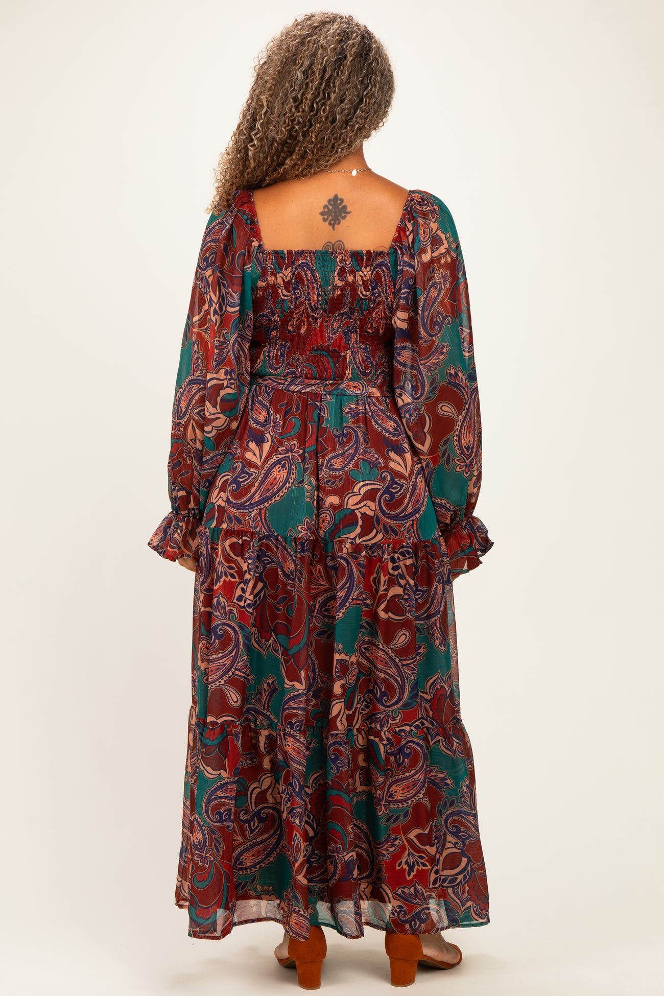 woman wearing a colorful paisley print plus size maxi dress with long sleeves and ruffled cuffs, shown from the back
