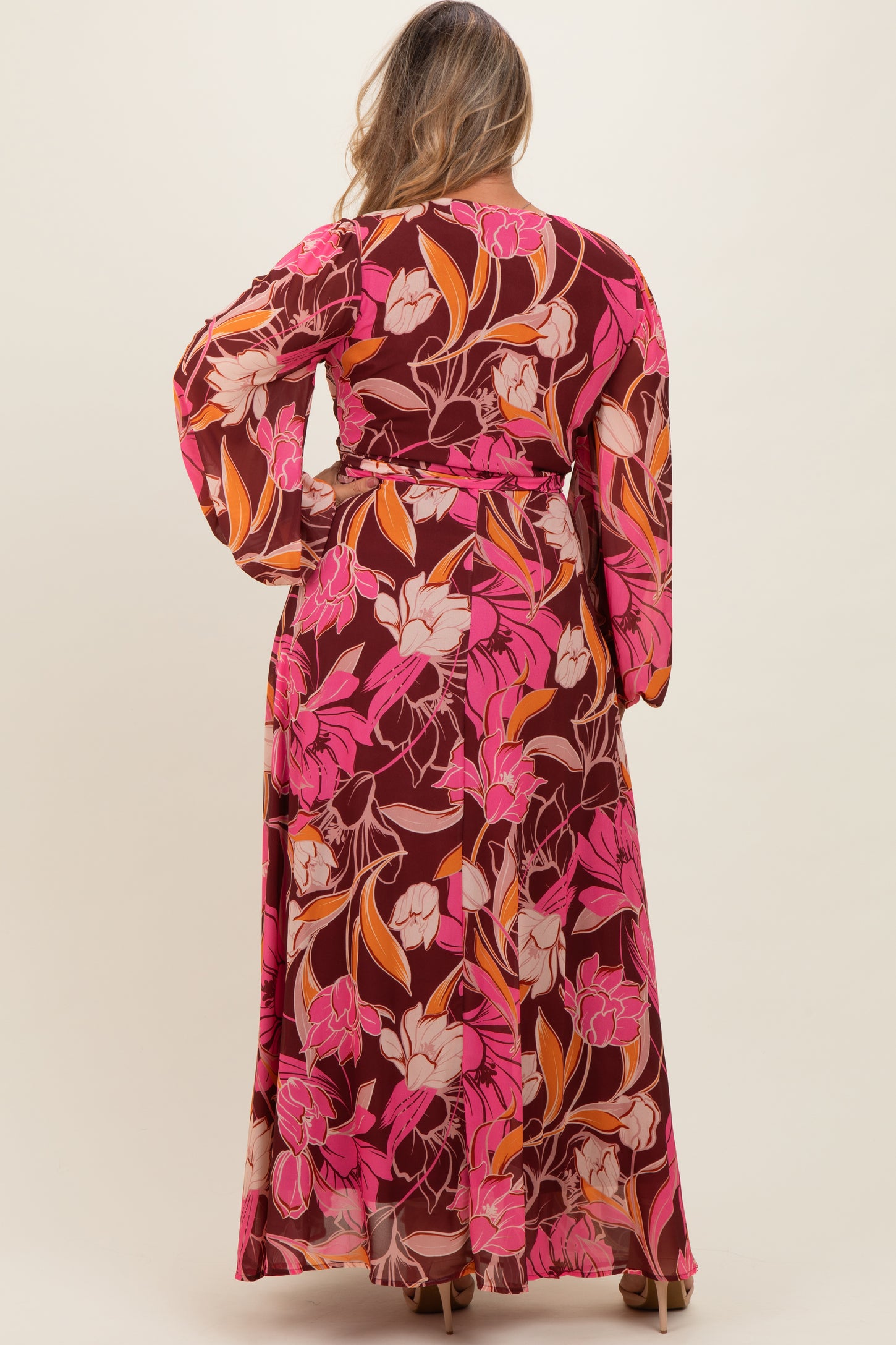 woman wearing a floral print maternity plus maxi dress with long sleeves and a tie waist, showing the back view