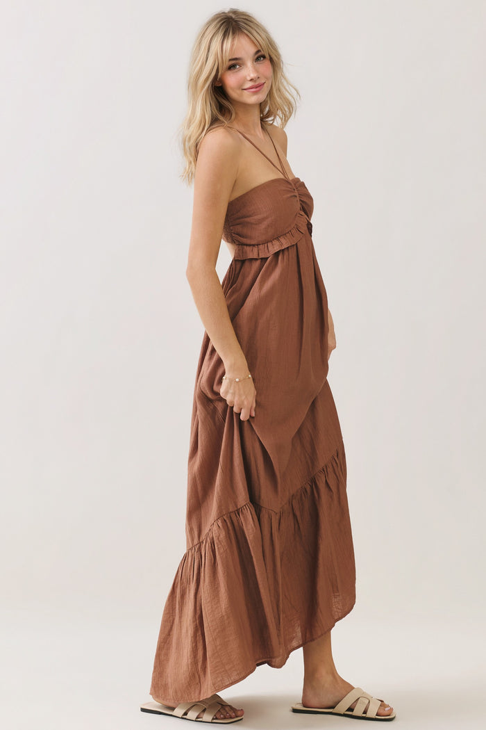 woman wearing a rust-colored strapless maxi dress with a ruffled bodice and tiered skirt