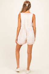 woman wearing a light pink floral maternity romper with a cinched waist and shorts, viewed from the back
