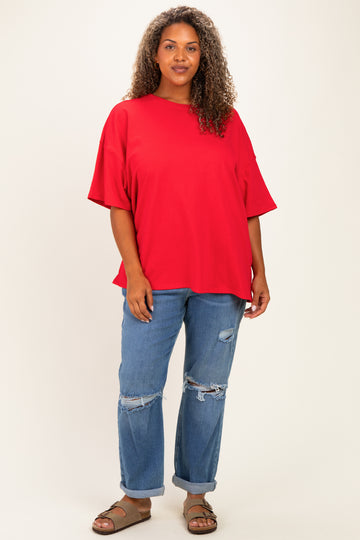 woman wearing a bright red oversized t-shirt and distressed blue jeans with brown sandals