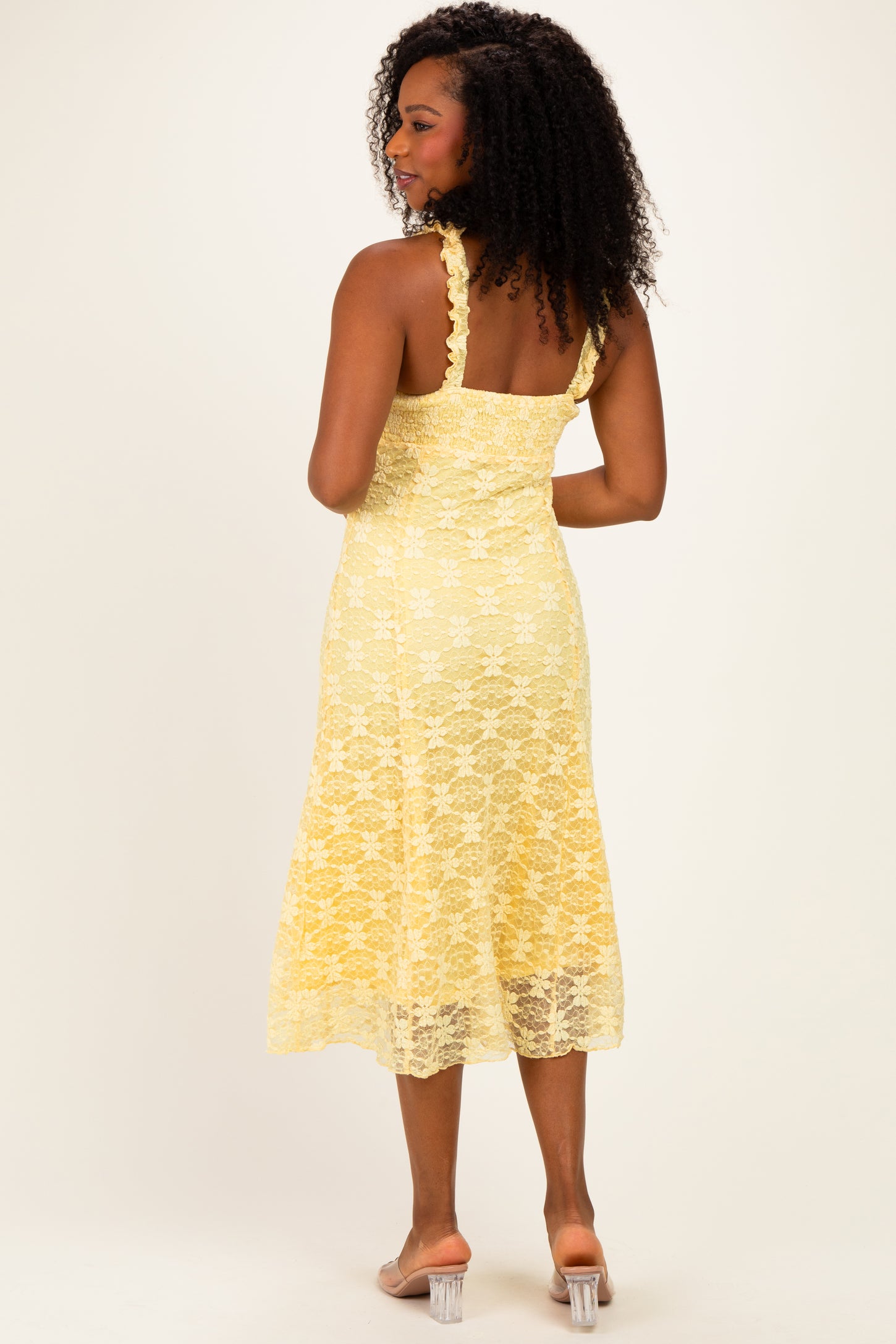 woman wearing a yellow lace midi dress with intricate floral detailing and spaghetti straps, shown from the back